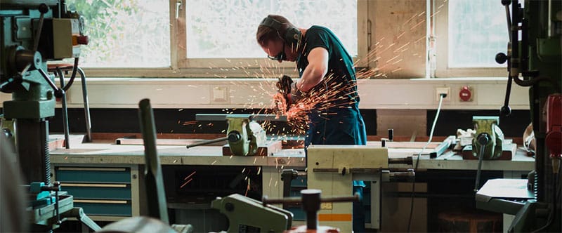 Image d'un homme dans un atelier en train de découper du métal avec une scie circulaire